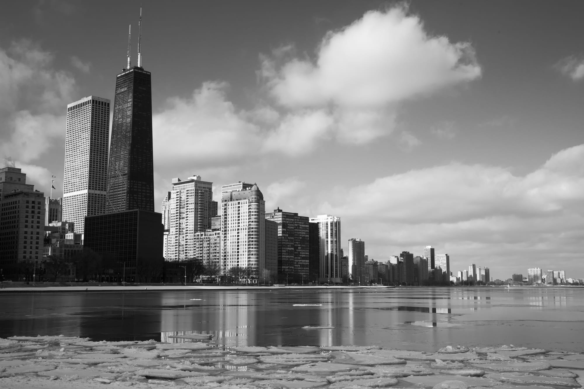 a black-and-white photograph of several Chicago buildings with Lake Michigan and ice in the foreground